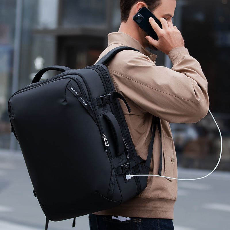 Mark Ryden black multi-functional large capacity backpack worn by man talking on phone in city