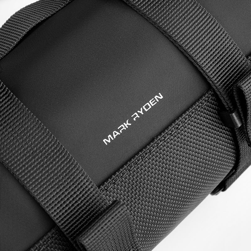 Close-up of black Mark Ryden MotoBarrel cylinder crossbody bag with adjustable strap, showcasing durable fabric and brand logo.