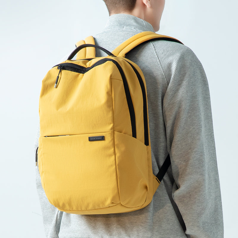 Bright yellow ultra-light backpack with black accents, worn by person in gray sweater | Mark Ryden Global
