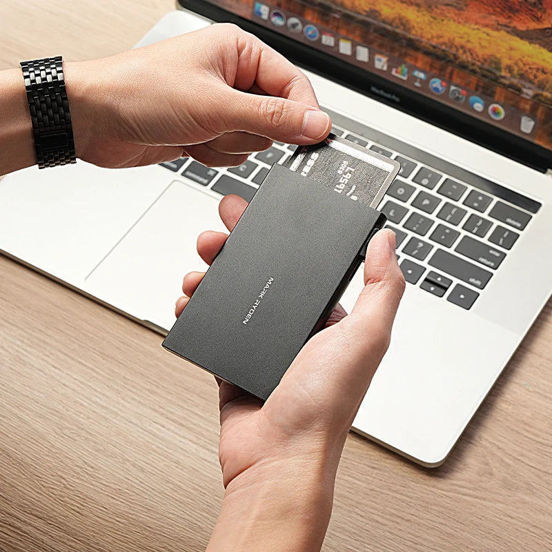 Mark Ryden black ultra-thin metal card holder protecting cards by laptop