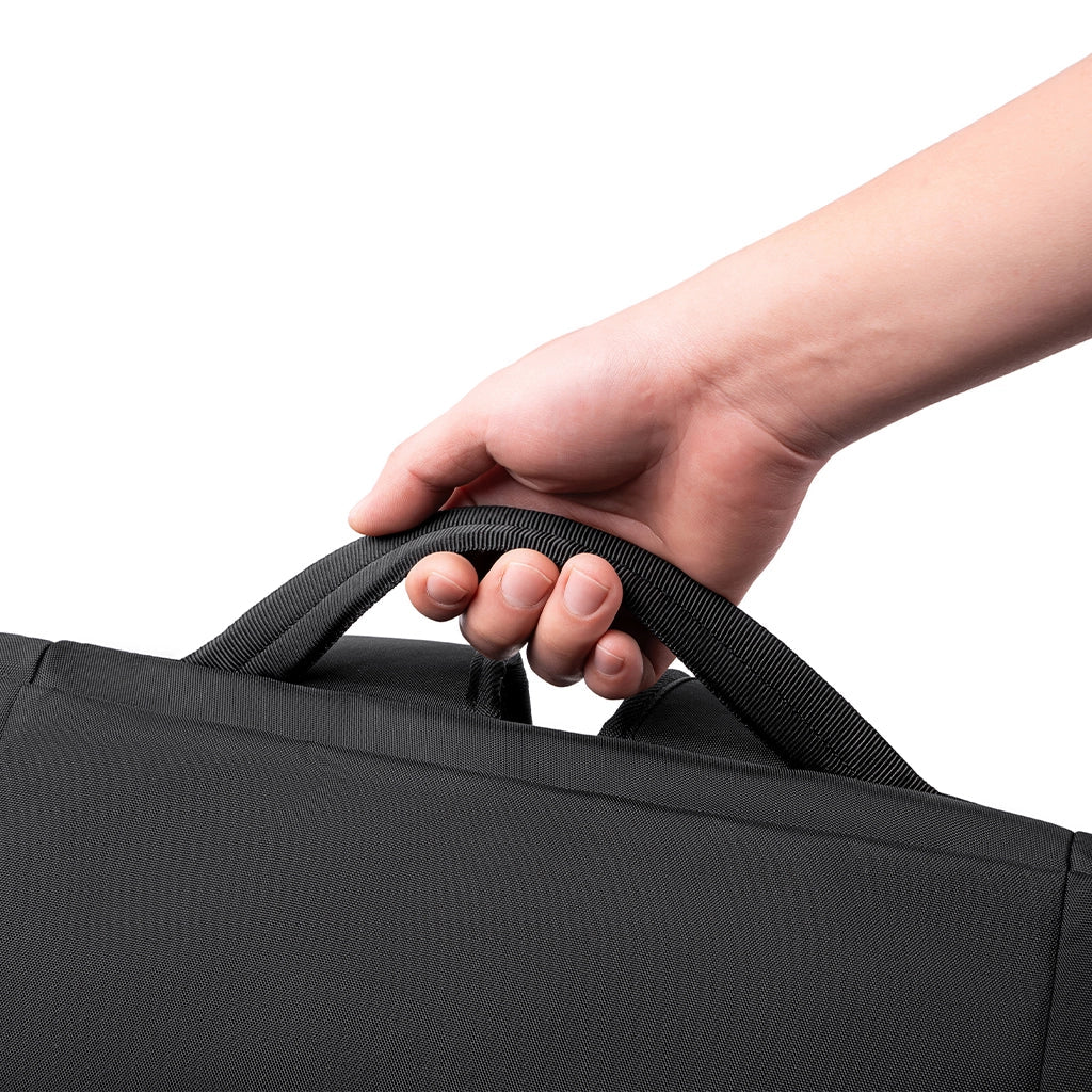 Hand gripping black MorphCore travel backpack handle