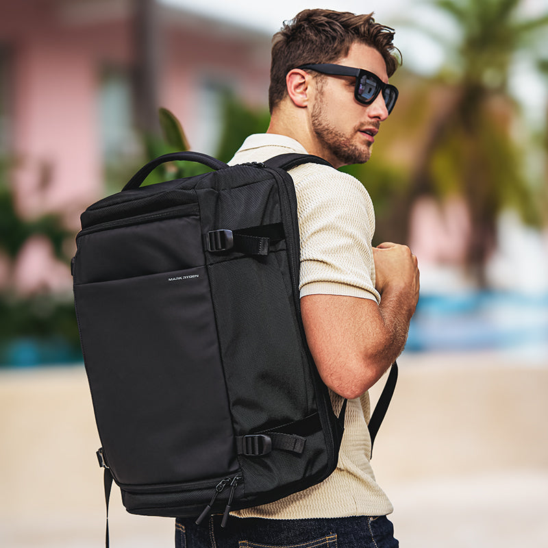 Mark Ryden Global Aegis Fortress 38L backpack worn by traveler outdoors - black multi-compartment design